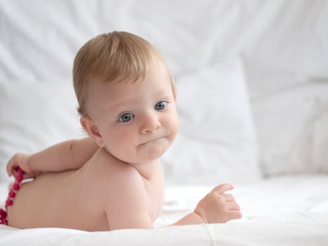 Baby on Bed Playing With Beads photo