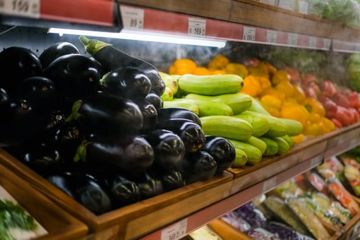 The grocery store sells various vegetables, tomatoes, cucumbers, eggplants, peppers, zucchini. Vegetables are on the shelf in the grocery store. photo