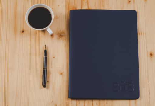 personal organizer or planner with fountain pen and hot coffee on wood table. photo