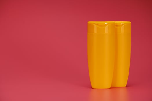 Two Yellow Blank Label Shampoo Bottle or Shower Gel on Pink Background photo