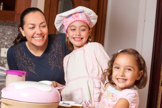 Mother and daughters having fun in the kitchen baking together. Preparing cupcakes with mom photo