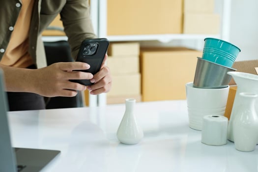 Young male online business owner using cellphone checking parcel box. photo
