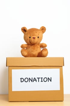 Kid Donation, Charity, Volunteer, Giving and Delivery Concept. Bear doll and Clothes with Donation box at home for support and help poor, refugee and homeless people. Copy space for text photo
