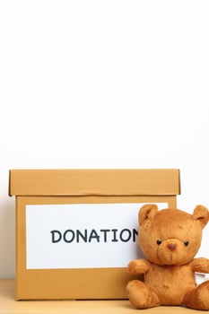 Kid Donation, Charity, Volunteer, Giving and Delivery Concept. Bear doll and Clothes with Donation box at home for support and help poor, refugee and homeless people. Copy space for text photo