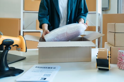Young entrepreneur packing product in mailing box for shipping. photo