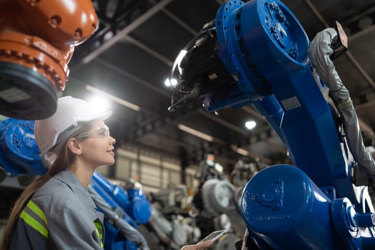 A female engineer installs a program on a robotics arm in a robot warehouse. And test the operation before sending the machine to the customer. photo