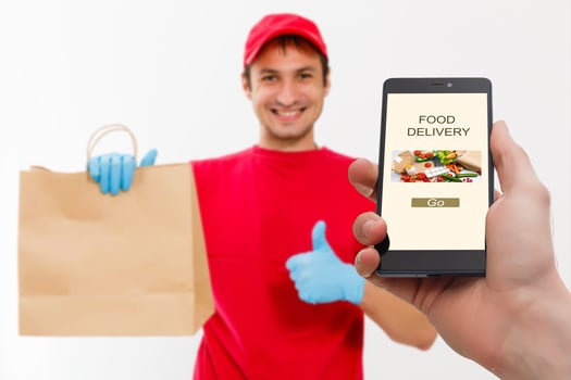 delivery food service at home. Man courier delivered the order no name bag with food. Hand holding smart phone with food online device on screen photo
