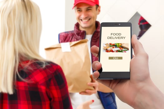 delivery food service at home. Man courier delivered the order no name bag with food. Hand holding smart phone with food online device on screen photo