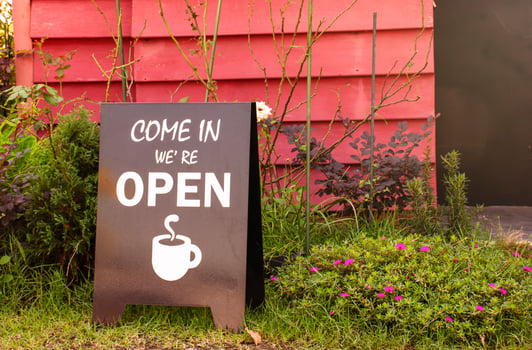 Brown sign with message COME IN WE'RE OPEN and icon coffee cup on glass at entrance coffee shop photo