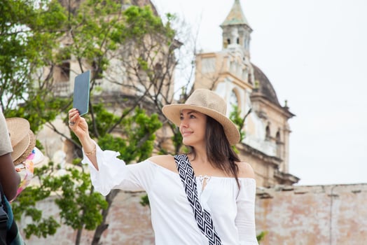 Beautiful young woman trying on hats to buy one from an street vendor in Cartagena de Indias walled city photo