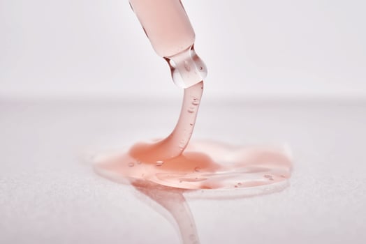 Pipette with a viscous pink cosmetic close-up. photo