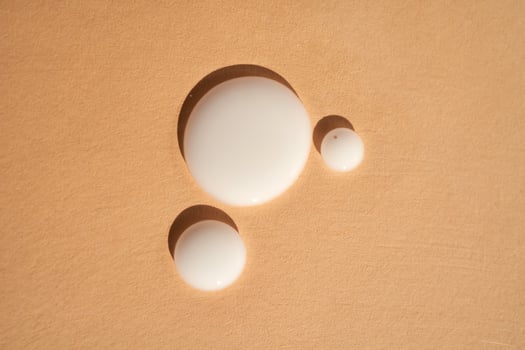 Drops of white milk on a beige background. photo
