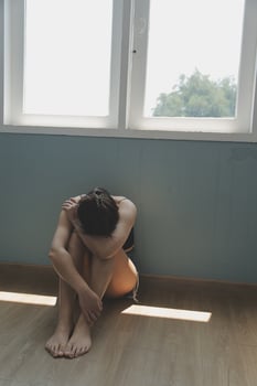 Thoughtful girl sitting on sill embracing knees looking at window, sad depressed teenager spending time alone at home, young upset pensive woman feeling lonely or frustrated thinking about problems photo