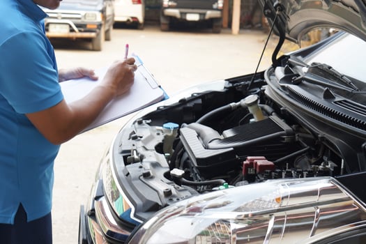 Closeup man mechanic inspecting car engine. holds paper, checking and analyzing car engine under the hood. Concept, Outdoor car inspection service. Claim for accident insurance. photo