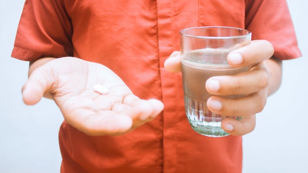A person holding medicine and drink on a white background photo
