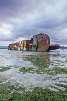 Shipwreck on the white sand beach of Pangandaran, West Java, Indonesia. the ship was sunk due to illegal fishing photo
