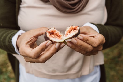 Two halves of a fresh, juicy and sweet red and violet fig freshly picked from the tree, holding in woman hands photo