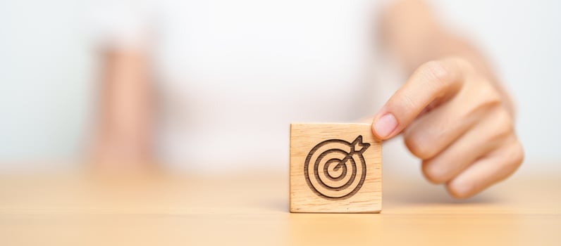 hand hold dartboard block with business goal, strategy, target, mission, action, objective, aim and success concept photo