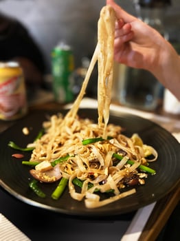 Asian food - noodles with chicken in soy sauce with spinach and green onion on black plate photo