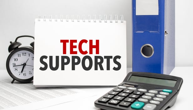 tech supports words on white notebook and calculator, black vintage alarm clock and blue paper folder photo