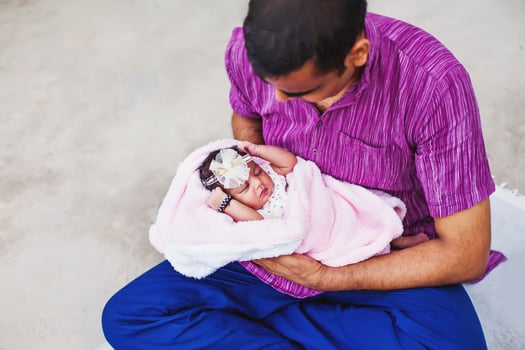 a man holding a baby in a pink blanket photo