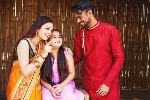 Happy beautiful Indian mother, father and daughter pointing finger at something photo