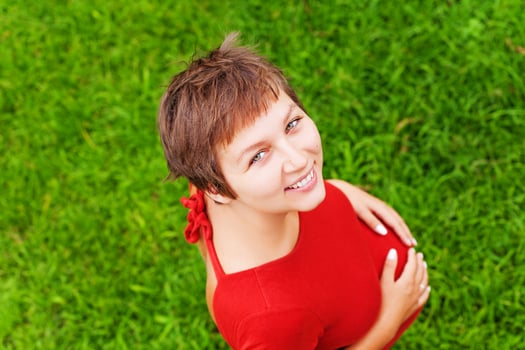 Young pregnant mom expecting a baby. She is standing over green grass photo