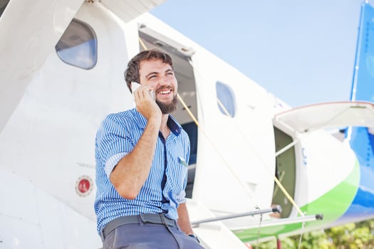 a man talking on a cell phone while sitting in front of a plane photo