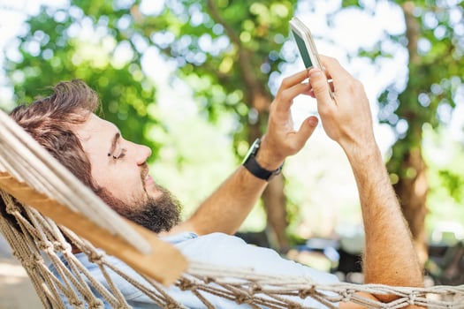 closeup of a caucasian man using mobile phone white swinging in a hammock photo