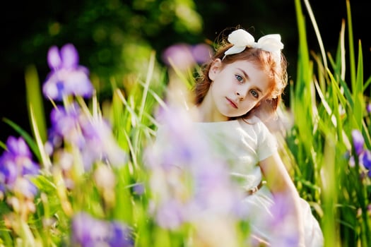 a little girl is standing in the grass with her hands on her head photo