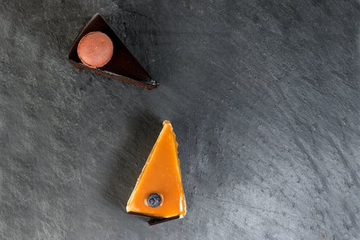 Chocolate cream caramel macaroon cake slice on black slate marble photo
