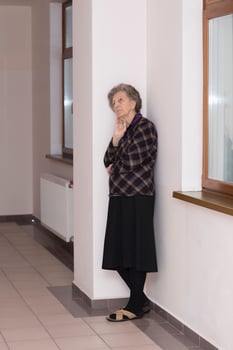 Old woman of 80 years old stays close to the window photo