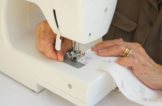 An old tired woman who is working on a sewing machine photo