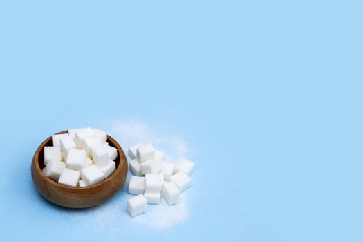 refined sugar in a wooden cup on a blue background with copy space photo