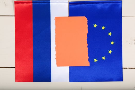 Two flags of EU and Russia on a white wooden surface. Top view photo