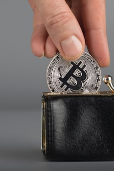 Person puts bitcoin in a black wallet. photo