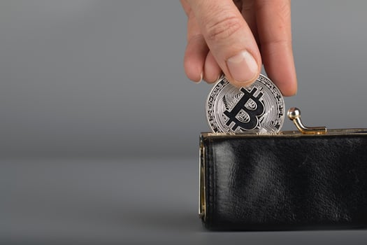 Person puts bitcoin in a black wallet. photo