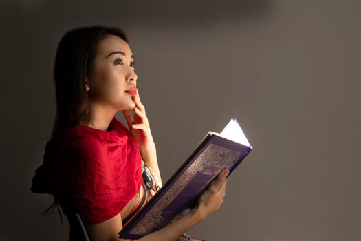 Asian woman opening mystic book box magical light dark background photo