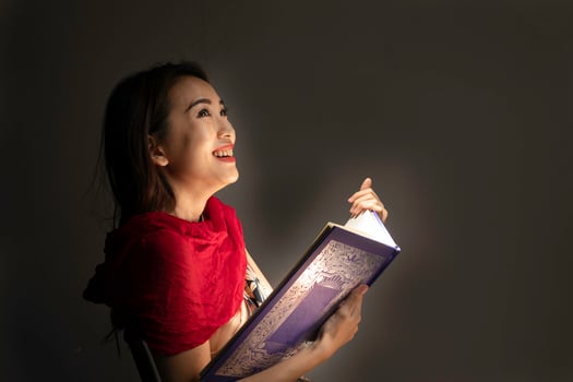 Asian woman opening mystic book box magical light dark background photo