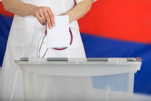 Doctor's hand casts ballot paper in the ballot box. photo