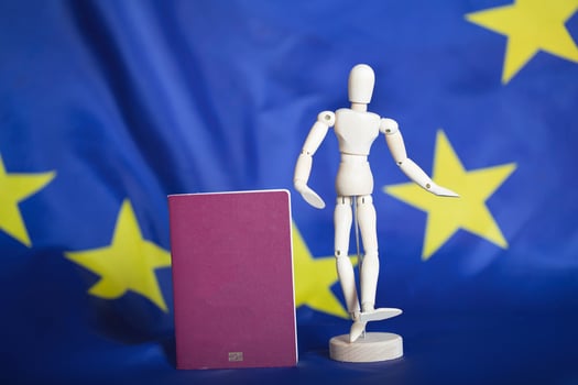 Biometric passport and dummy figurine in front go EU flag. photo