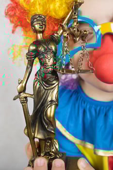 Statue of Themis in the hand of five years old child dressed in clown costume. photo