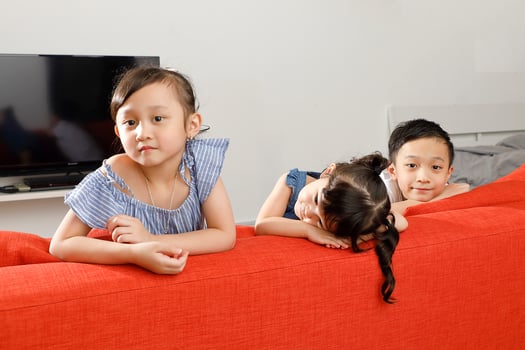 Three little child boy girl brother sister happy smile looking over the sofa photo