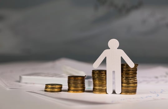 Paper cutout of a person in front of coins stacks. photo