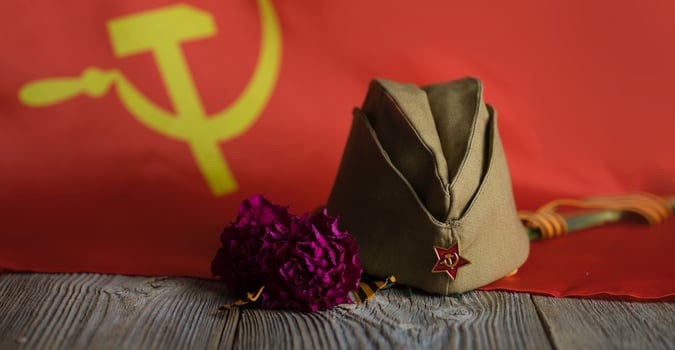 Military cap, carnations, Saint George ribbon on a wooden surface. photo