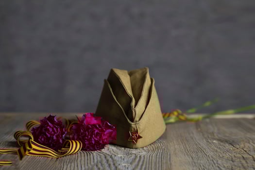 Military cap, carnations, Saint George ribbon on a wooden surface. photo