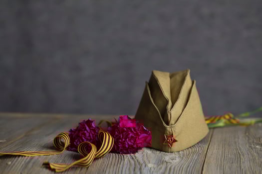 Military cap, carnations, Saint George ribbon on a wooden surface. photo