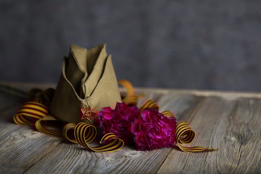 Military cap, carnations, Saint George ribbon on a wooden surface. photo