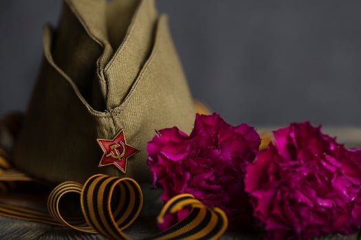Military cap, carnations, Saint George ribbon on a wooden surface. photo