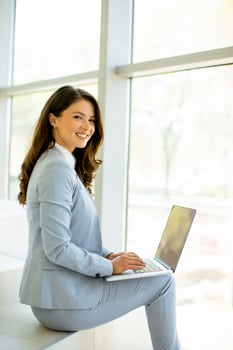 Young business woman sitting on the stairs on office hallway and working on laptop photo